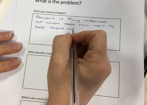 Close-up photo of someone filling out a form titled 'What is the problem?'