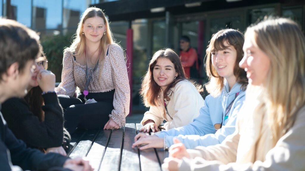 Group of students sitting around a table outside chatting